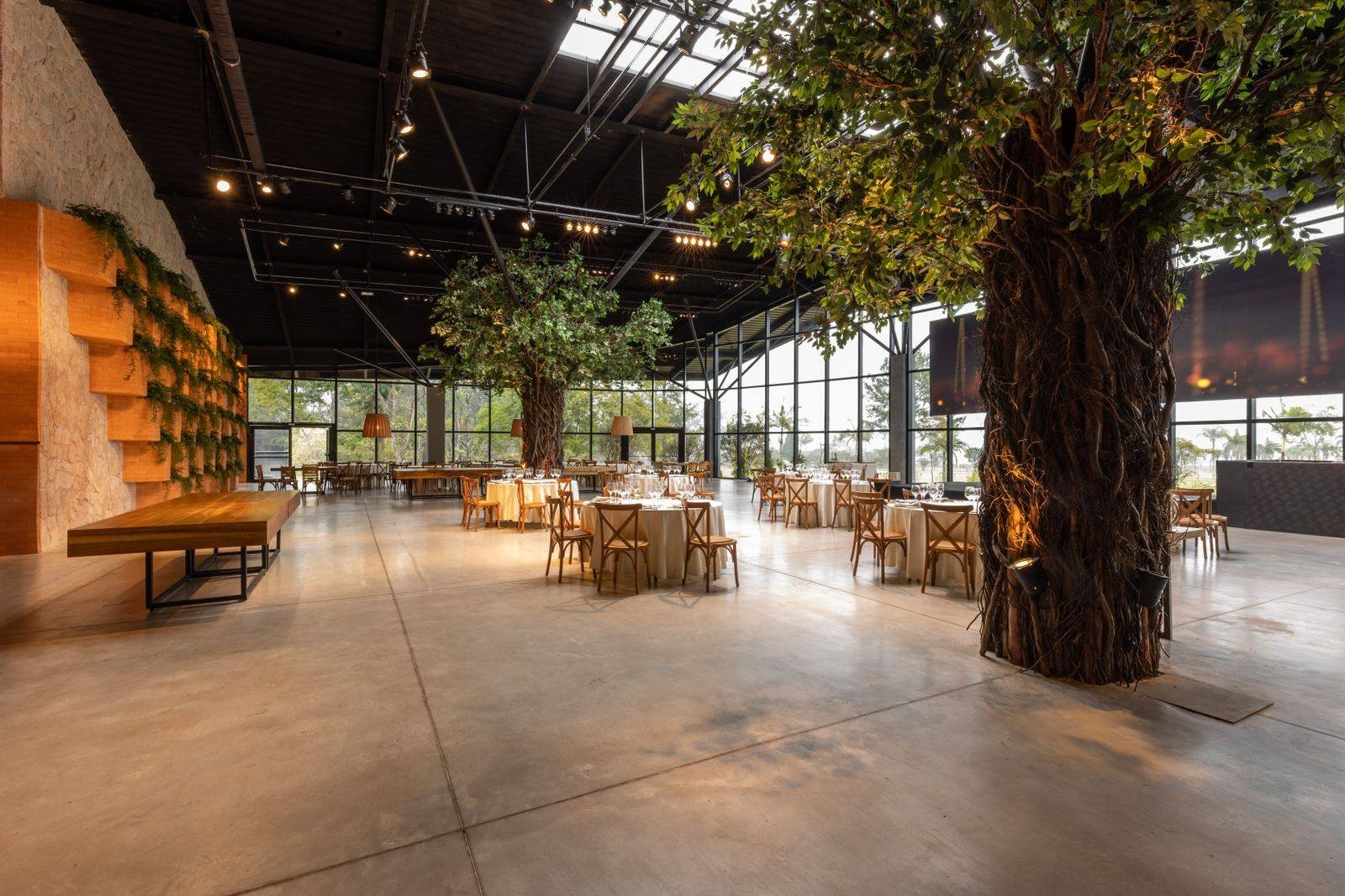 Salón para evento corporativo ambientado con árboles y plantas naturales